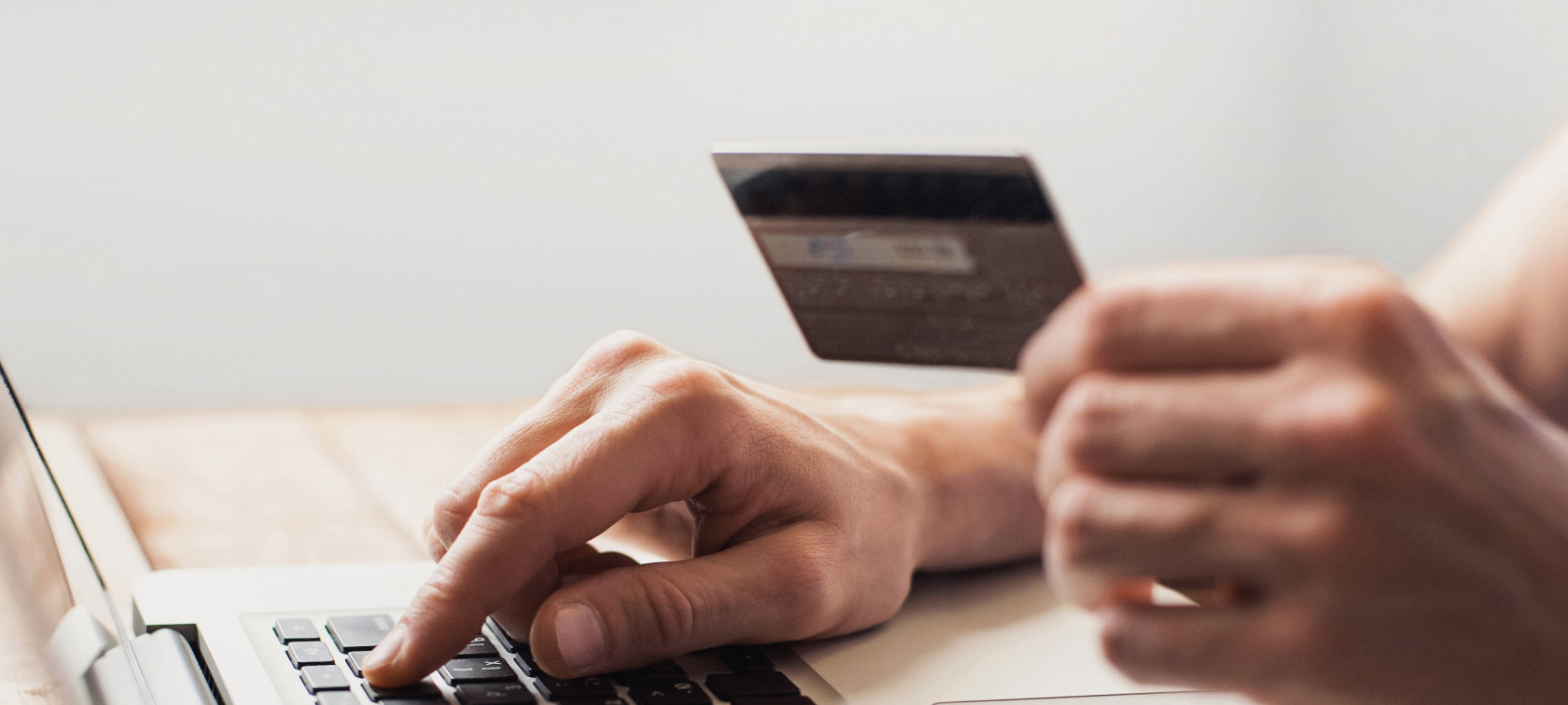 Woman shopping on her laptop with credit card in her hand