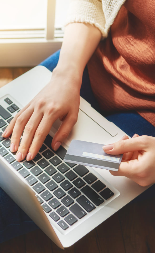 Woman shopping on her laptop with credit card in her hand