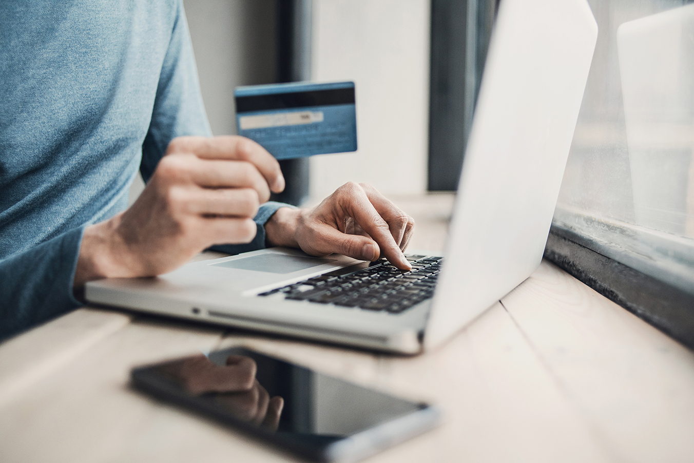 man shopping on computer with credit card in hand